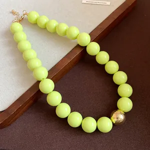 Detailed view of neon yellow chunky bead necklace featuring a striking gold metallic bead