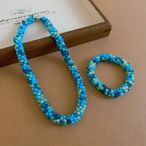 Detail shot of the woven crystal beaded necklace and bracelet set in blue and green.