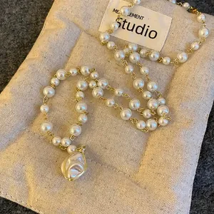 Close-up detail of baroque pearl necklace with irregular pendant on linen bag background