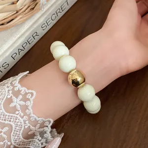 Close-up detail of chunky cream and gold bead bracelet on a wrist with lace sleeve