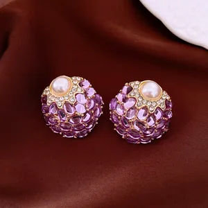 Close-up detail of vintage palace style earrings with purple gemstones and pearls on silk