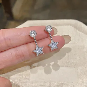 Close-up of dainty silver star drop earrings with sparkling zircon stones for women.