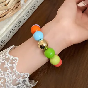 Close-up of a colorful beaded bracelet with large round beads worn on a wrist with lace.