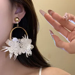 Dettaglio di eleganti orecchini a cerchio con fiori in pelle bianca su una modella
