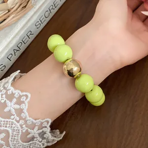 Detailed view of chunky lime green bead bracelet featuring a gold statement bead on wrist