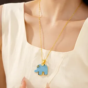 Detail of a light blue resin elephant pendant on a gold chain necklace worn by a model