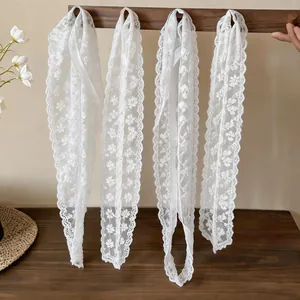 Close-up of white floral lace scarves with intricate patterns for hair and neck styling.