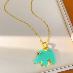 Macro view of a bohemian resin elephant pendant necklace with a gold chain in mint green