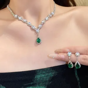 Detail showing the intricate crystal setting and vibrant green teardrop stones on the jewelry.