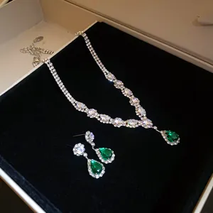 Detailed view of elegant silver necklace and drop earring set with emerald green stones
