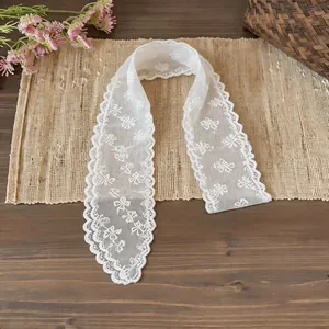 Detail view of a white lace ribbon scarf with delicate floral embroidery for hair or neck