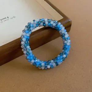 Detailed close-up of hand-woven beaded crystal bracelet in blue and white ocean tones.
