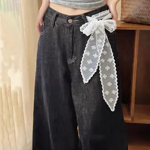 Close-up of white lace ribbon bow tied as a decorative waist belt on denim jeans