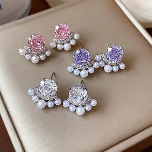 Macro view showing detailed pink, purple, and white flower zircon and pearl stud earrings