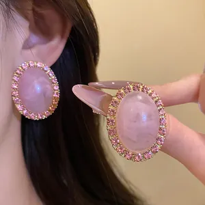Elegant detail of vintage pink acrylic oval stud earrings with sparkling rhinestone border