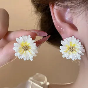 Primo piano di orecchini a margherita in smalto bianco che mostrano la trama dei petali