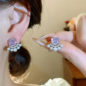 Macro view of silver needle stud earrings featuring a purple zircon flower and pearls.