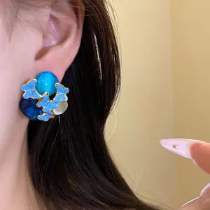 Close-up detail showing a vintage blue enamel butterfly earring with blue gems worn on an ear