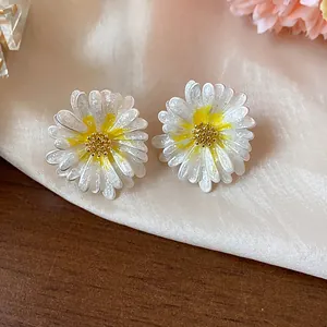 Dettaglio di eleganti orecchini a lobo a margherita bianca con smalto giallo