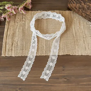 Detail shot of white floral lace ribbon scarf with delicate embroidery patterns