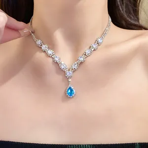 Close-up of silver necklace with sparkling blue water-drop zircon pendant on model