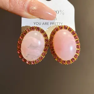Detail of vintage-style pink marble acrylic stud earrings with rhinestone halo in gold