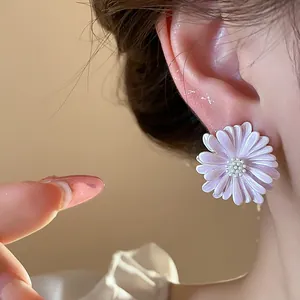 Primo piano di un orecchino a lobo margherita viola indossato, con petali di smalto.