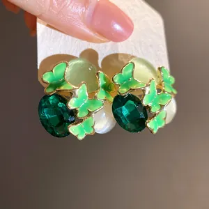 Detailed macro shot of vintage emerald green butterfly stud earrings with stones