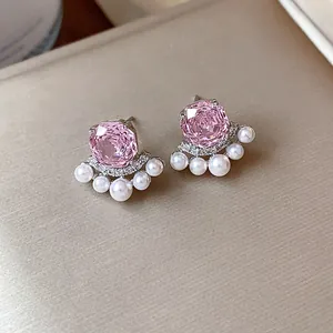 Detailed view of elegant pink zircon stud earrings with small white pearls and crystals