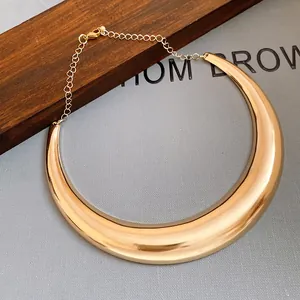 Primo piano di una collana girocollo in metallo dorato lucido in stile vintage.