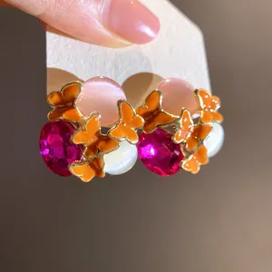 Detailed view of vintage butterfly earrings with pink cat-eye stones and magenta crystals