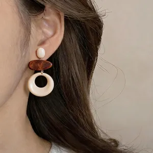 Eleganti orecchini rotondi in legno e resina indossati da una modella asiatica