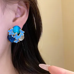 Close-up detail of vintage blue oil-dripped butterfly stud earrings worn on a model ear