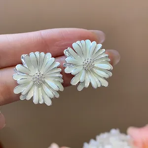 Dettaglio ravvicinato di eleganti orecchini a lobo a margherita in argento con petali smaltati.