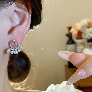 Close-up view of elegant French-style pink zircon flower and pearl stud earring worn on ear