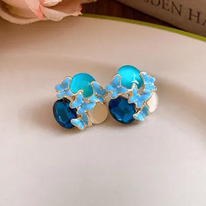 Close-up of blue drip oil butterfly earrings with rhinestones and cat-eye stones