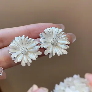 Primo piano di eleganti orecchini a margherita in smalto bianco con raffinati dettagli argento