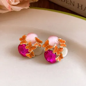 Macro view of vintage butterfly earrings with pink cat-eye and magenta rhinestones.