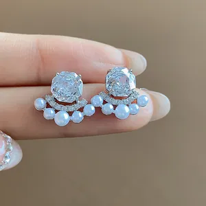 Close-up of French style earrings with clear zircon and pearls on silver needles