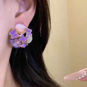 Close-up of purple butterfly enamel earrings with faceted crystal on model's ear