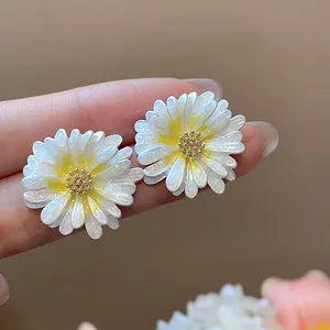 Dettaglio orecchini a lobo margherita bianco e giallo con smalto glitterato e perno argento.
