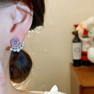 Close-up of elegant purple zircon flower earrings with small pearl fan-shaped design