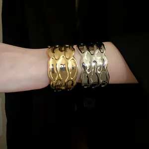 Detailed macro view of vintage gold and silver wavy textured metal open cuff bracelets for women.