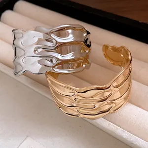 Close-up view of gold and silver textured metal open bangles with wavy lava pattern