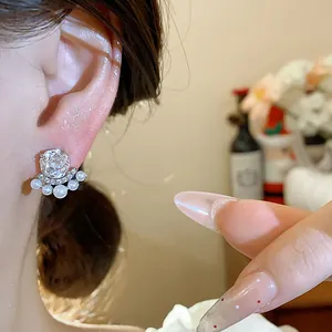 Close-up of elegant French style flower earrings with zircons and pearls on ear