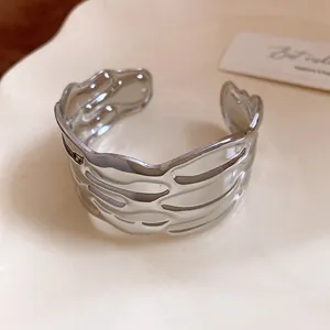 Close-up of silver-toned metal cuff bracelet with wavy textured striped design