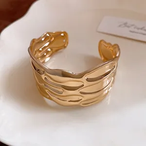 Detailed macro view of a vintage gold textured open cuff bracelet with elegant wavy patterns