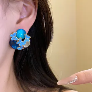 Close-up detail of a vintage butterfly stud earring with blue stones worn on an ear.