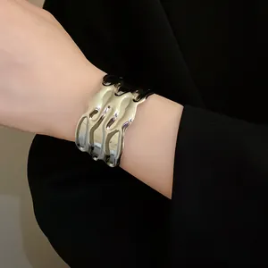 Close-up of a silver wavy metal cuff bracelet showing rippled texture on a wrist