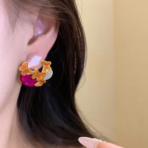 Close-up detail of vintage butterfly enamel stud earrings with colorful gemstones and silver needle